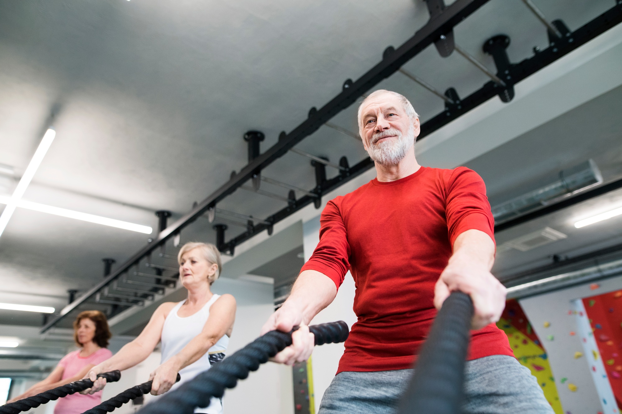 Seniors in gym working out with battle ropes